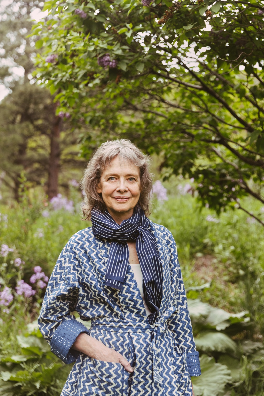 Connirae Andreas outdoors in a garden, smiling gently